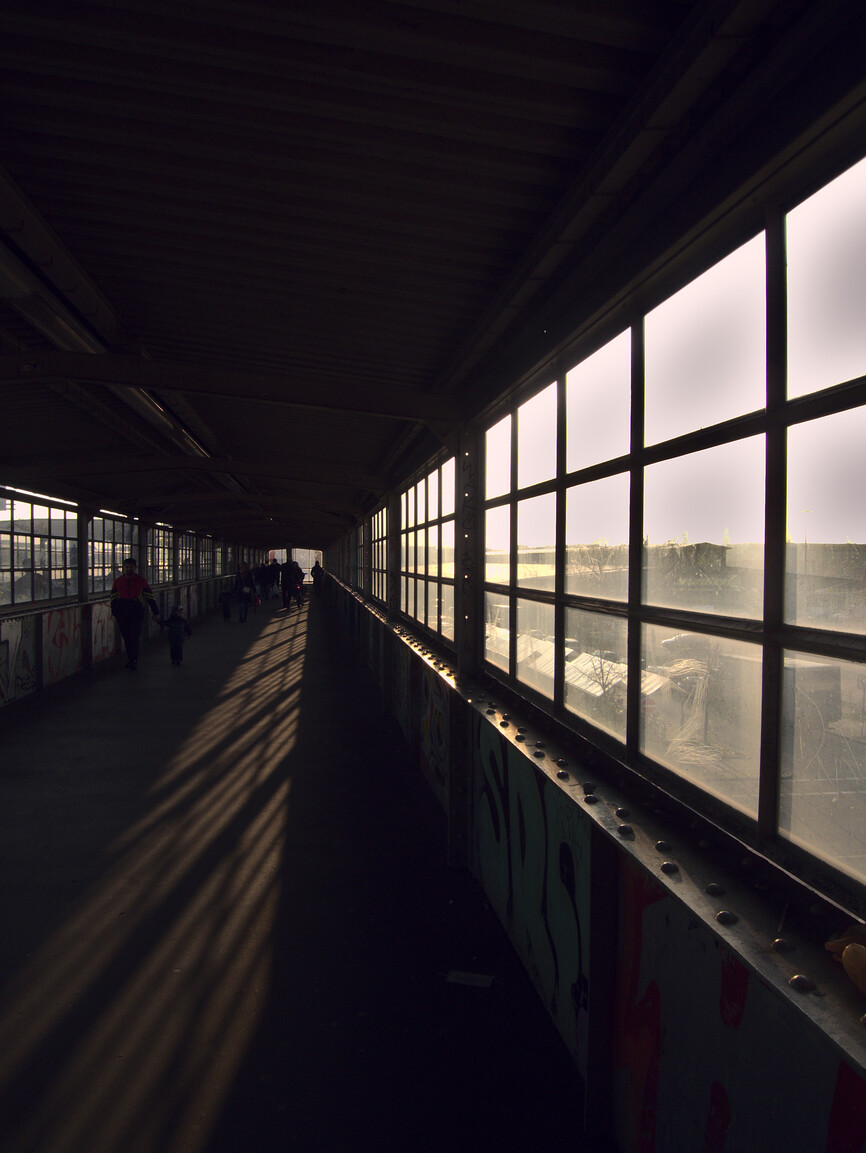Artistic photograph of a pedestrian overpass with light entering from the windows on the right hand side
